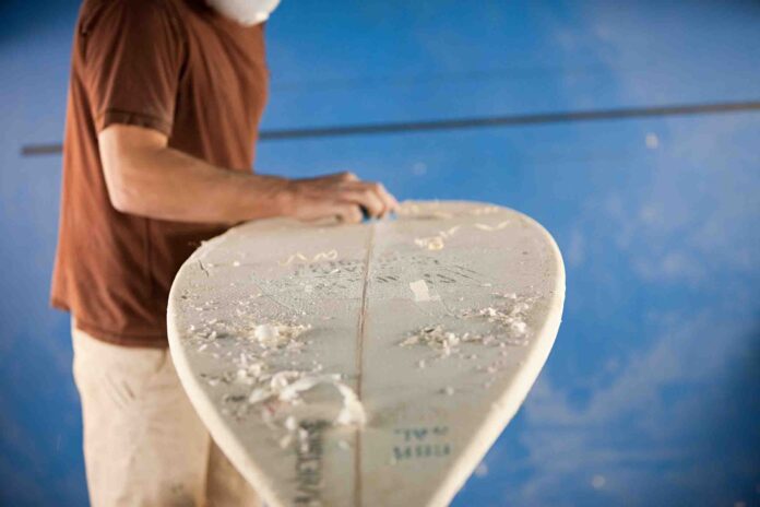 Man waxing surfboard man in the process of constructing a surfboard