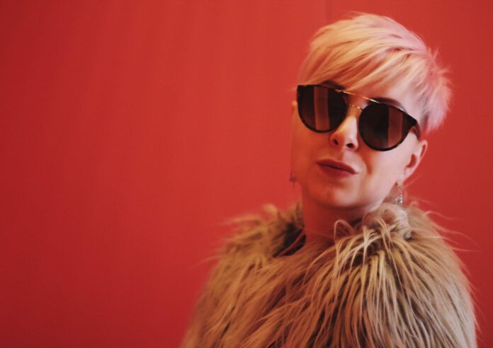daria-volkova-1459270-unsplash (1) woman wearing brown fur coat against a red backdrop