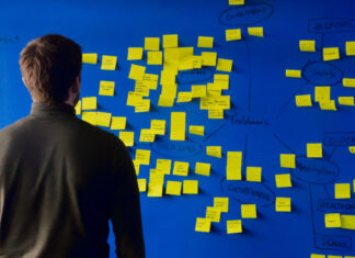 Coming up with unlimited fresh content ideas for a livestream Image of man standing in front of a bight blue wall with yellow sticky notes across a brainstorming diagram, presumably coming up with new content ideas