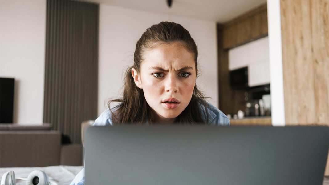 displeased-angry-girl-using-laptop-computer-3TUPMRX-scaled